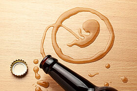 Alcohol and pregnancy. Bad habits. Beer bottle and spilled beer in the shape of an embryo