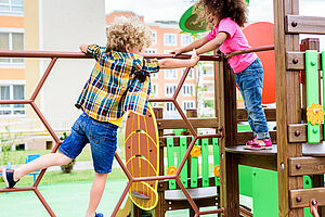 two multiethnic little kids climbing and having fun at playground