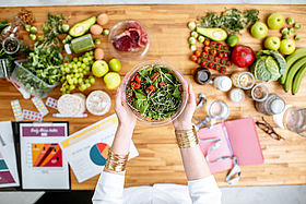 Dietitian holding salad above the table full of healthy food